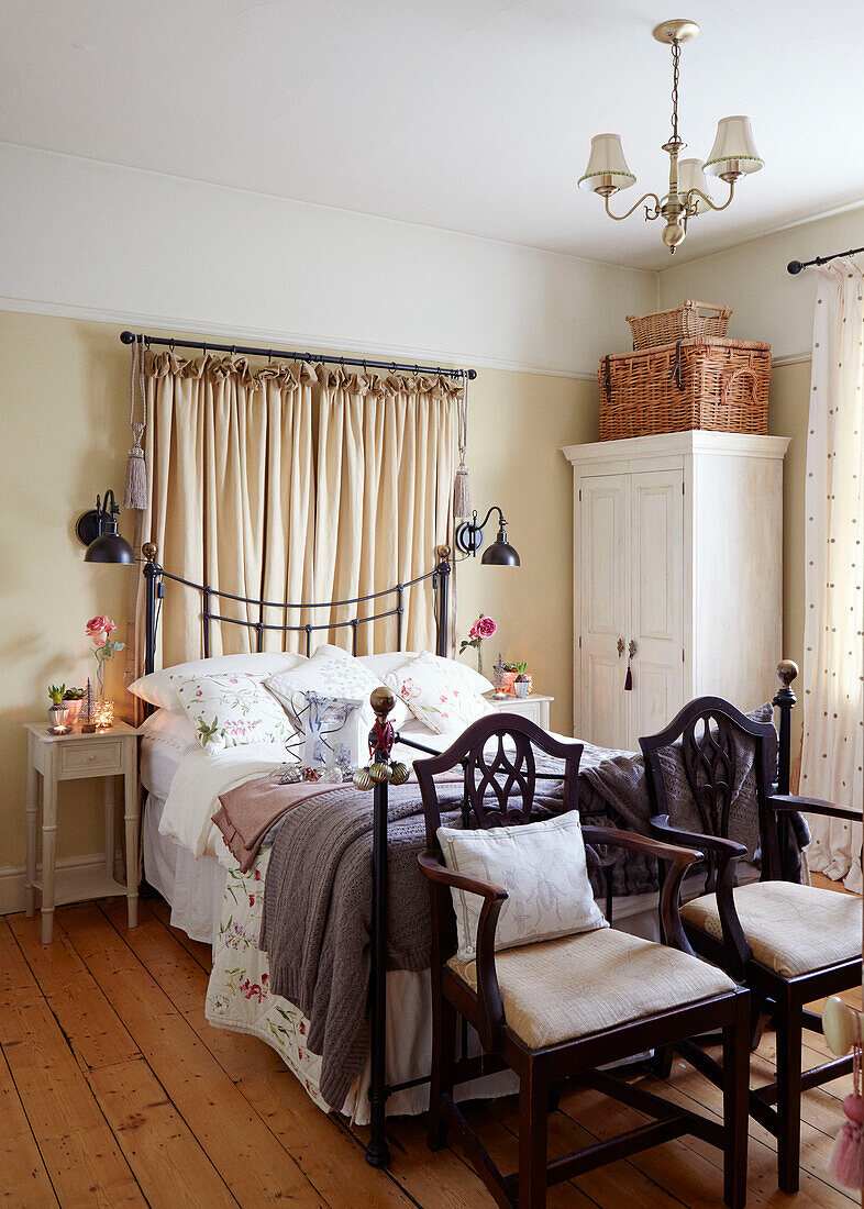 Pair of vintage chairs at foot of double bed in Chippenham home, Wiltshire, UK