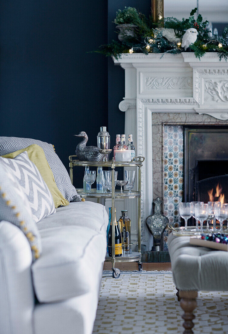 Service trolley and ottoman with sofa and lit fire in East Grinstead home, West Sussex, UK