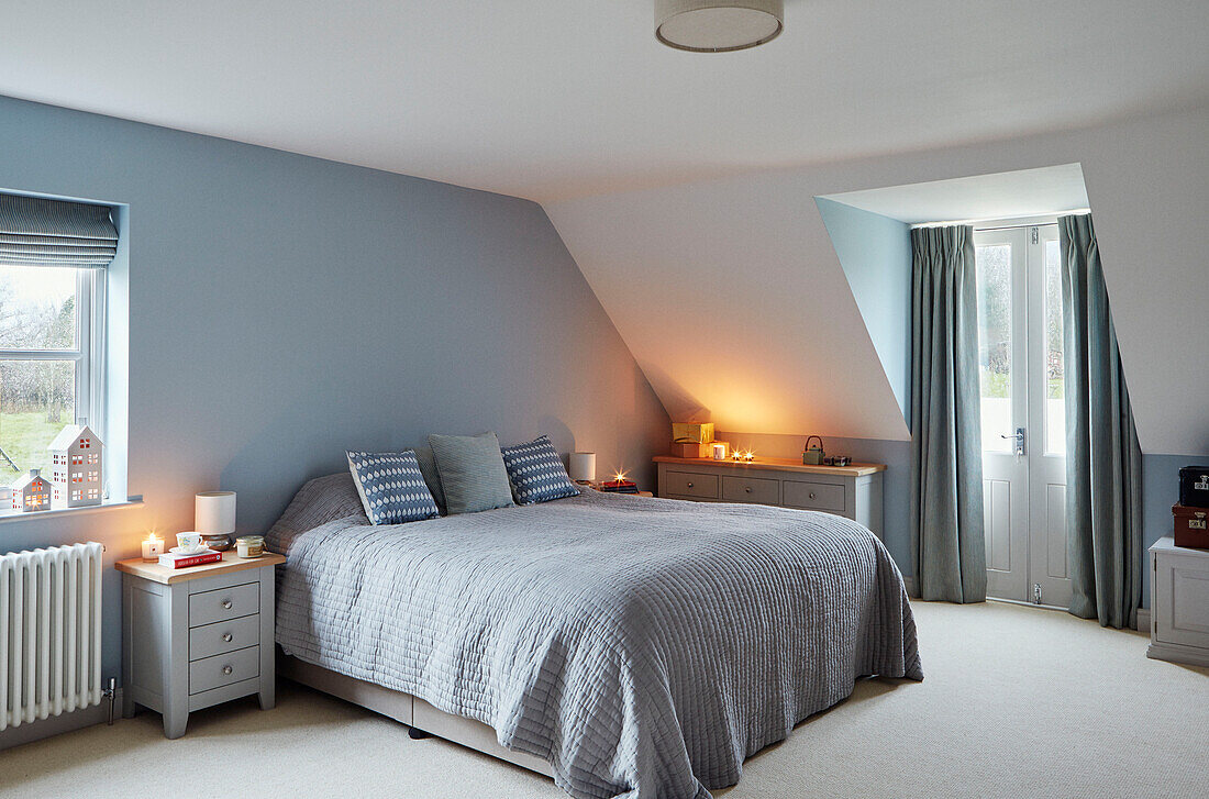 Green door curtains with lit candles in light blue Worcestershire bedroom, England, UK