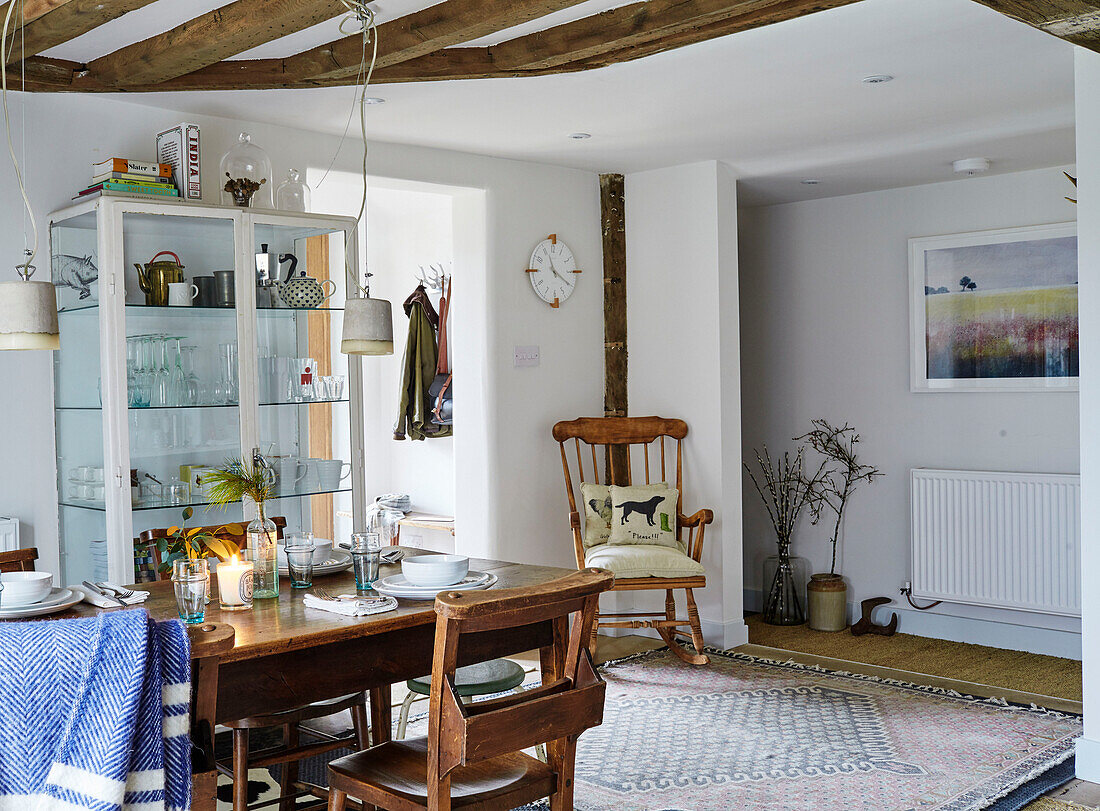 Wooden rocking chair and table with display cabinet in Warwickshire farmhouse, England, UK