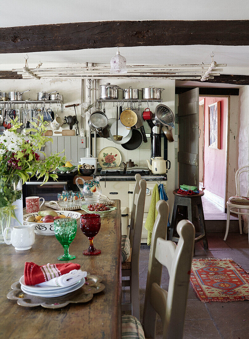 Pots and pans storage with wooden kitchen table in Powys cottage, Wales, UK