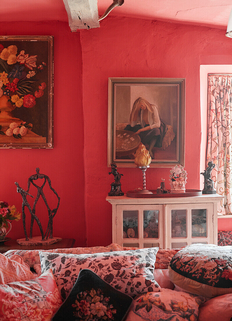 Framed artwork and ornaments with floral cushions on sofa in Powys cottage, Wales, UK