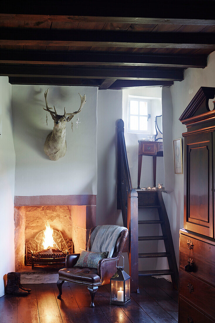 Leather chair at lit fireside in Scottish castle, UK