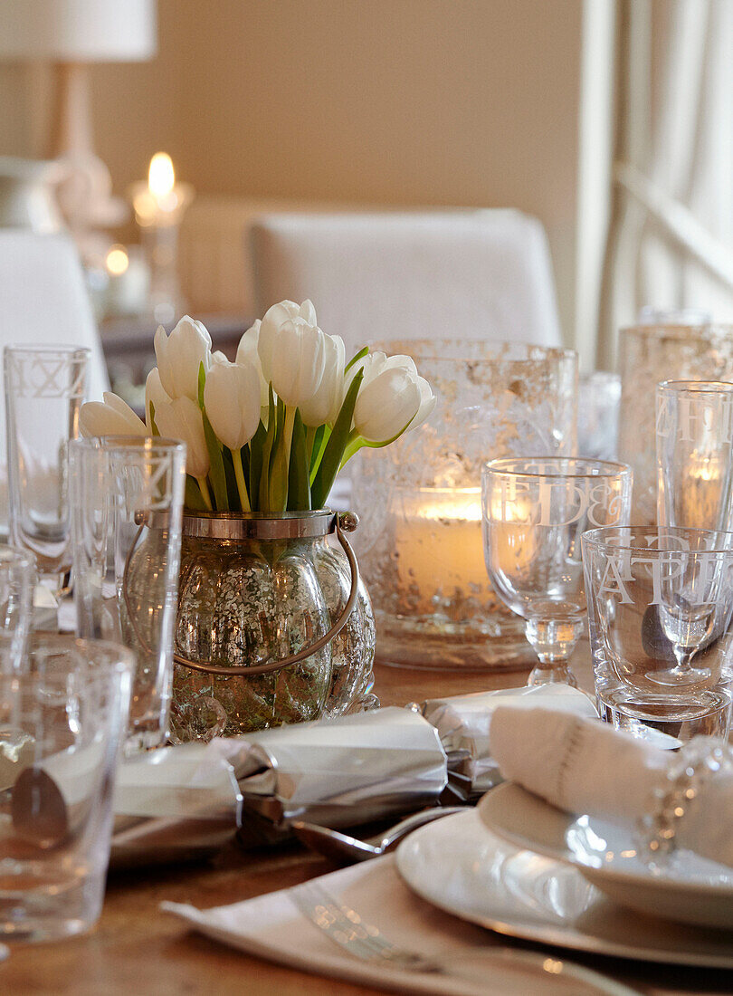 Weiße Tulpen und alte Glaswaren auf einem für das Weihnachtsessen gedeckten Tisch in einem britischen Haus