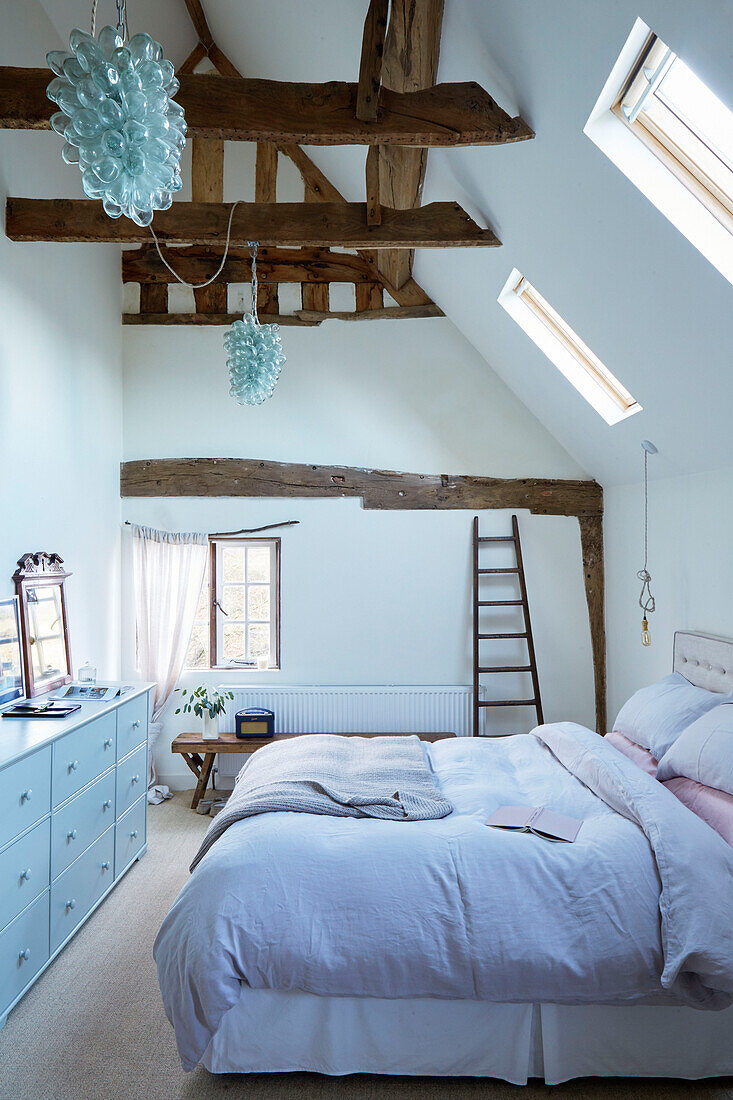 Coloured glass lights above double bed in Warwickshire farmhouse attic conversion, England, UK