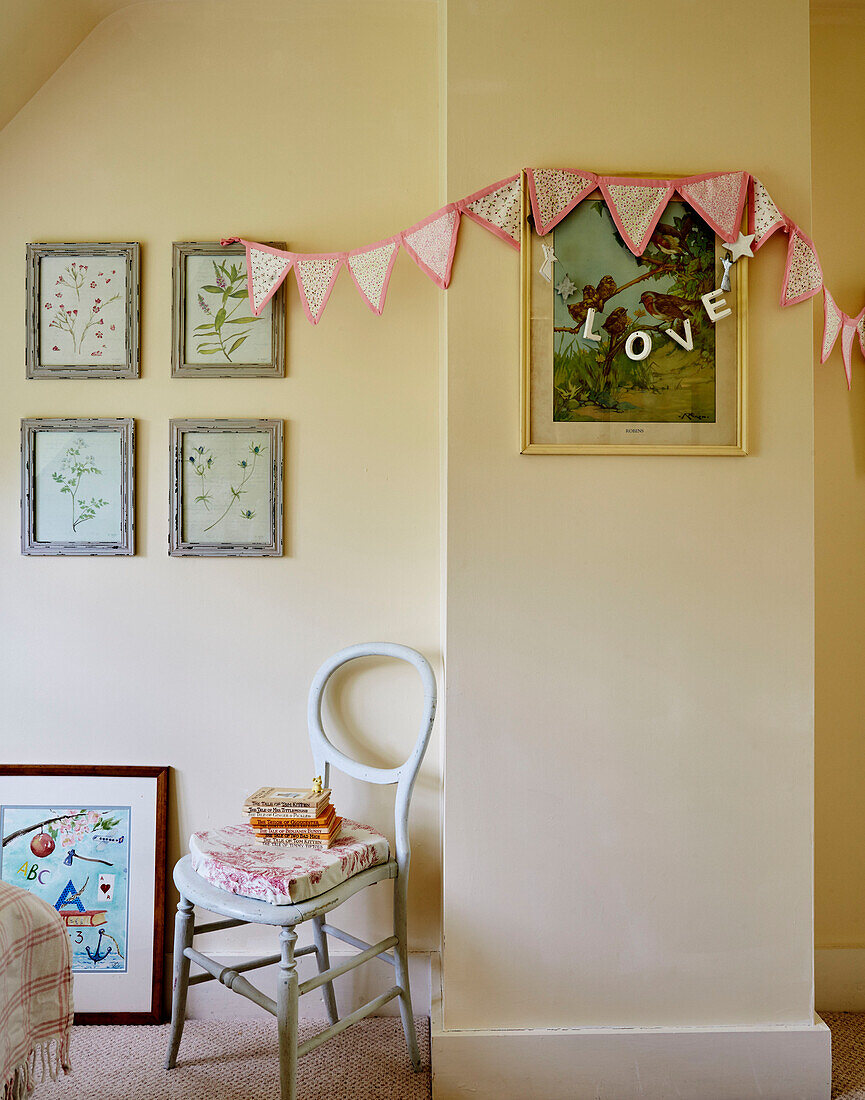 Botanische Motive und Wimpel mit Stuhl und Büchern in einem Cottage in Sandford St Martin, Oxfordshire, UK