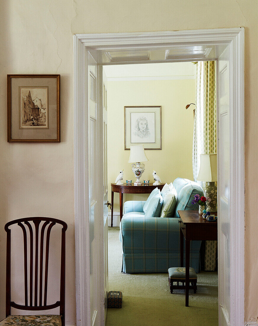 Blick durch die Tür auf ein türkisfarbenes Sofa in einem Haus in Syresham, Northamptonshire, UK