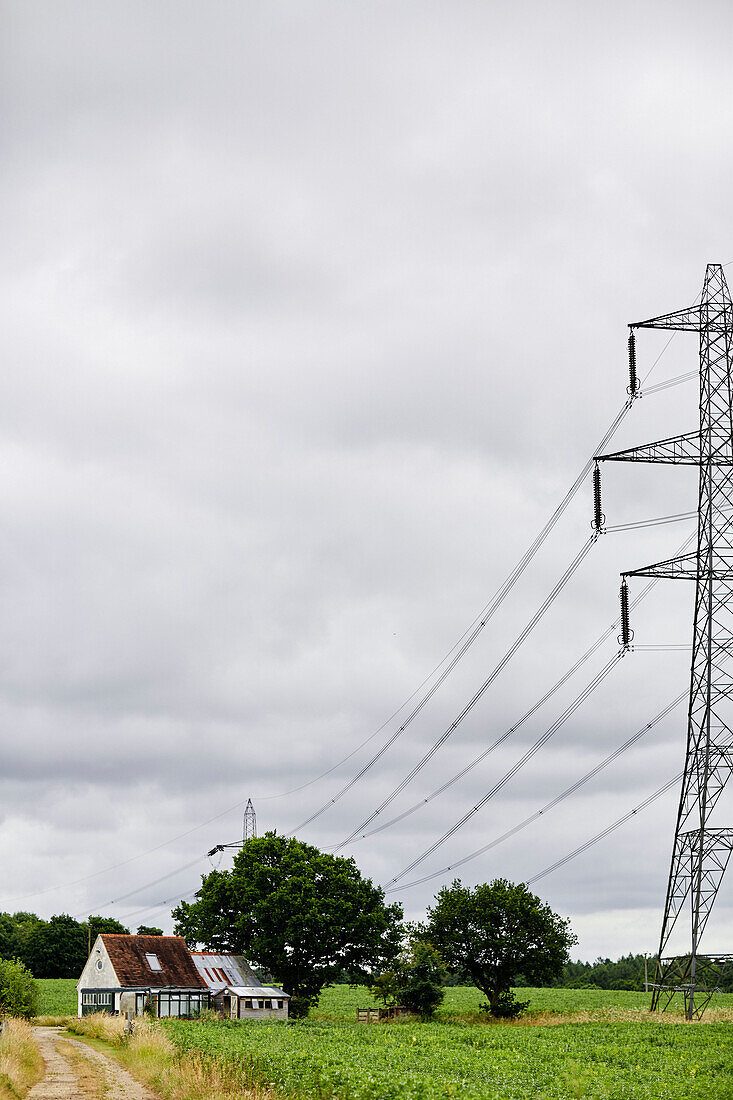 Ländliches Cottage auf einem Feld in Oxfordshire neben einem Strommast, UK