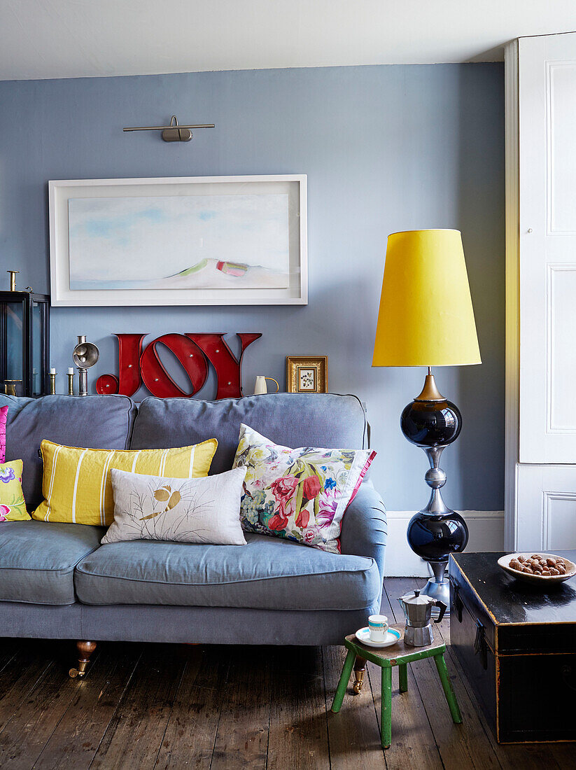 Large retro lamp and sofa with artwork and single word 'JOY' in Deddington home, Oxfordshire, UK