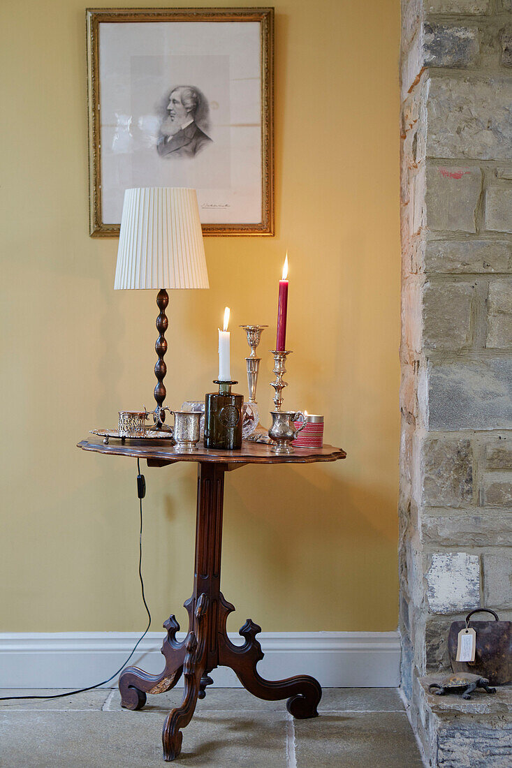 Lit candles on side table with gilt framed artwork in Northumberland farmhouse, UK