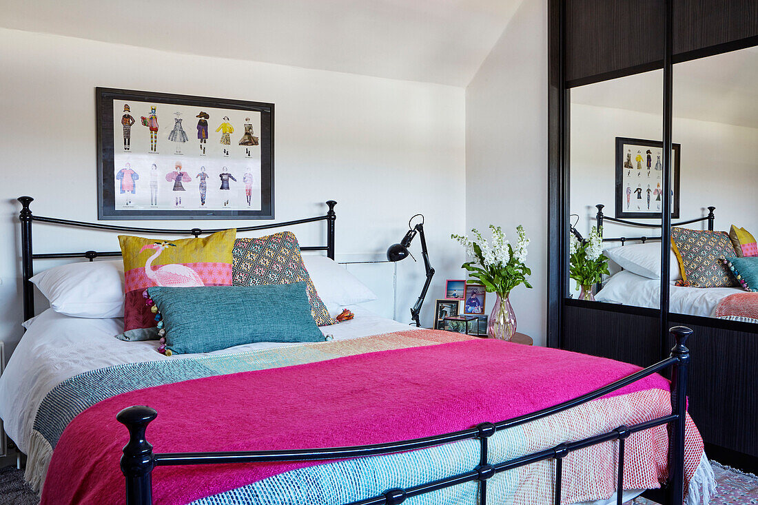 Bright pink blanket on bed in teen room with mirrored wardrobe 1960s dormer bungalow Holmfirth, West Yorkshire, UK