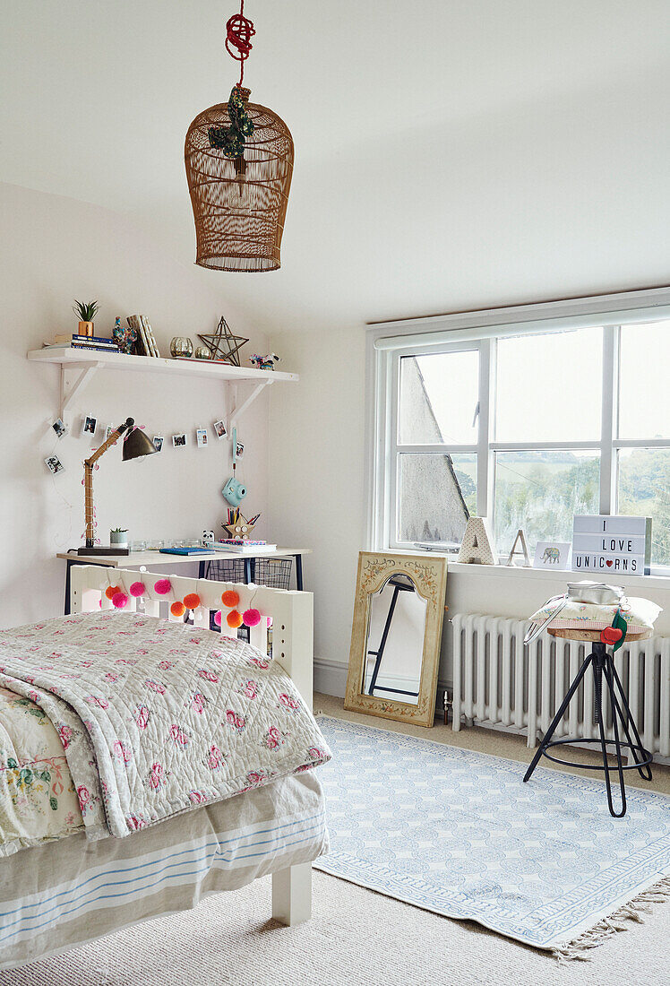 Floral quilt on single bed of girls room in Devon home, UK