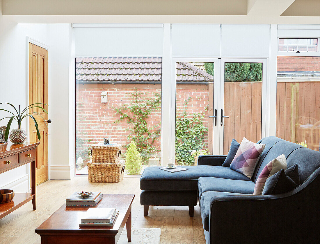 Ecksofa und Körbe mit Holztisch und gläsernen Terrassentüren in einem Haus in Durham, England, UK