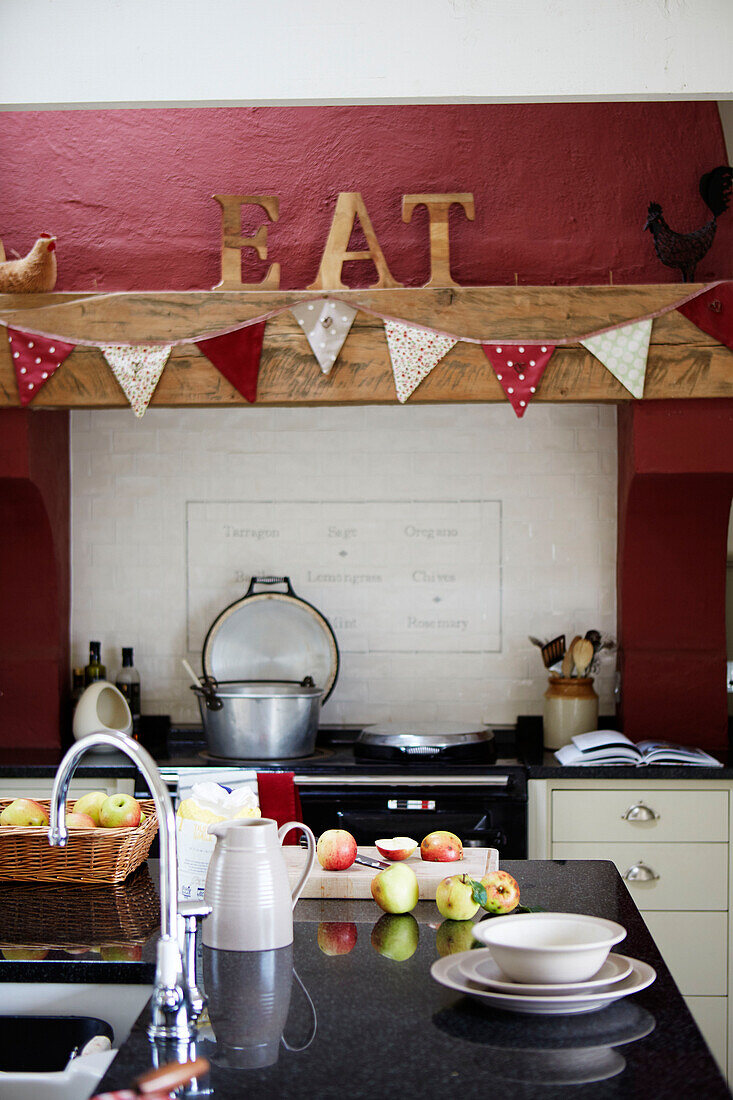 Cut apples on island unit with bunting above oven and single word 'EAT' in Northumberland farmhouse kitchen, UK