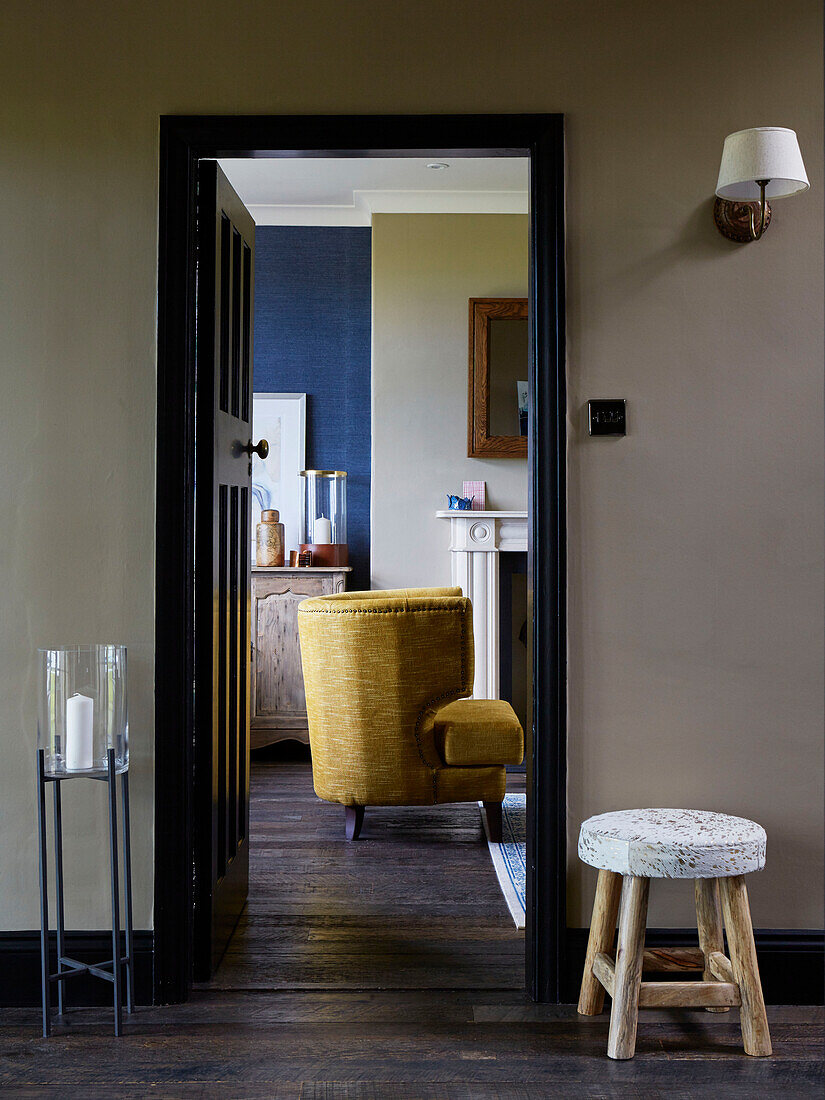 Upcycled armchair viewed through black doorframe in Northumbrian home, UK