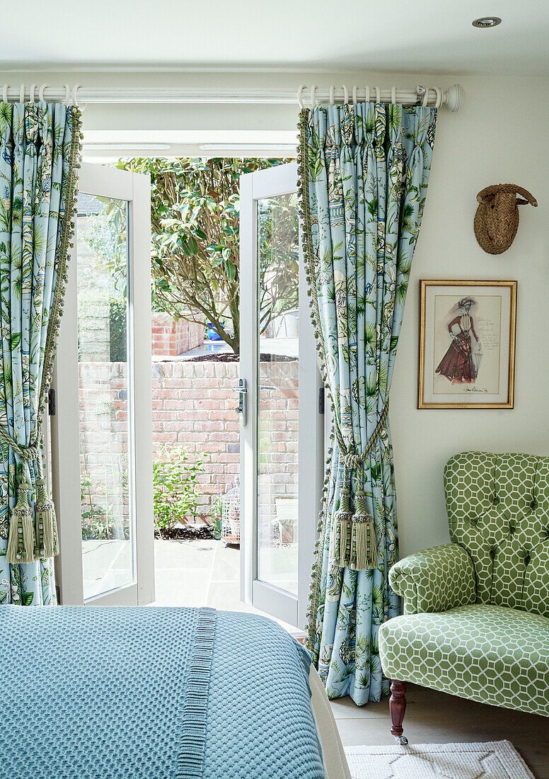 Blick durch die Gartentür zum Schlafzimmer mit kontrastierenden Stoffen in einem Cottage in den Cotswolds, UK