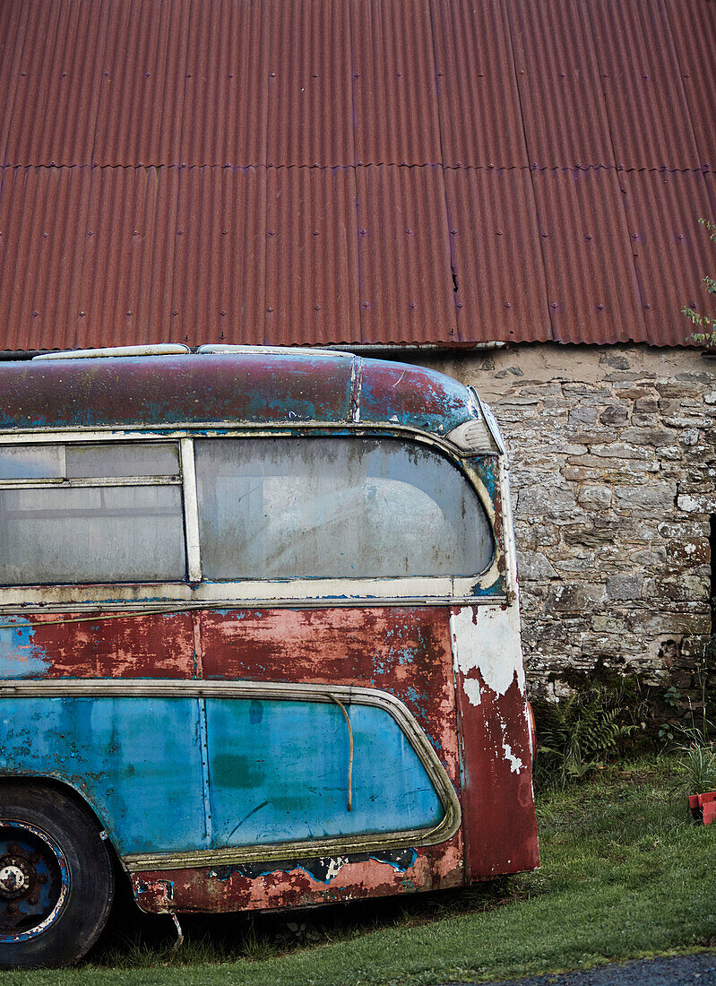 Alter blauer Bus vor einer Steinscheune mit Wellblechdach an der Grenze zwischen Radnorshire und Herfordshire