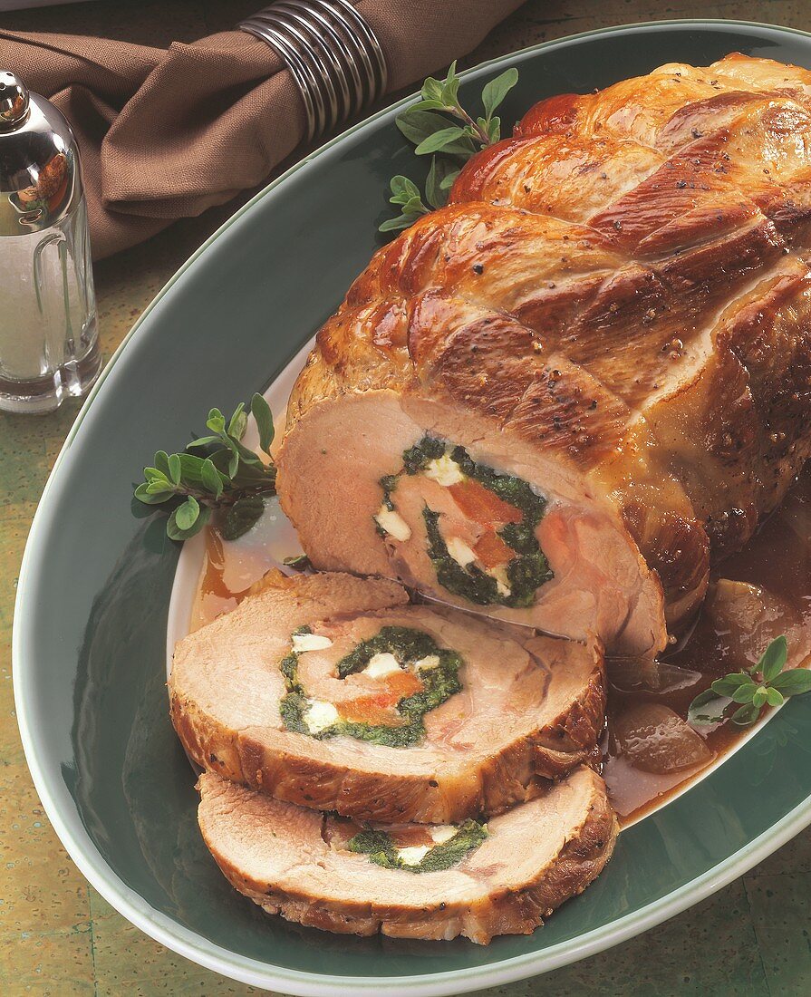 Schweinerollbraten mit Gemüse-Käse-Füllung auf ovaler Platte