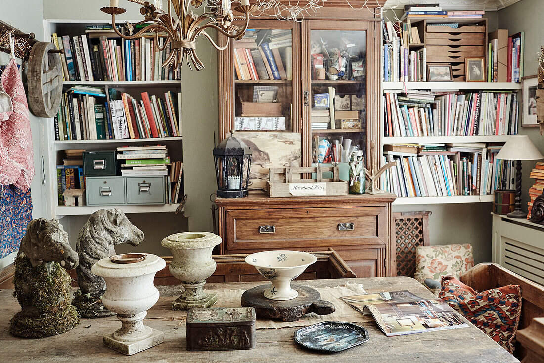 Glass fronted cabinet and books with horse statues and urns in Somerset home, UK