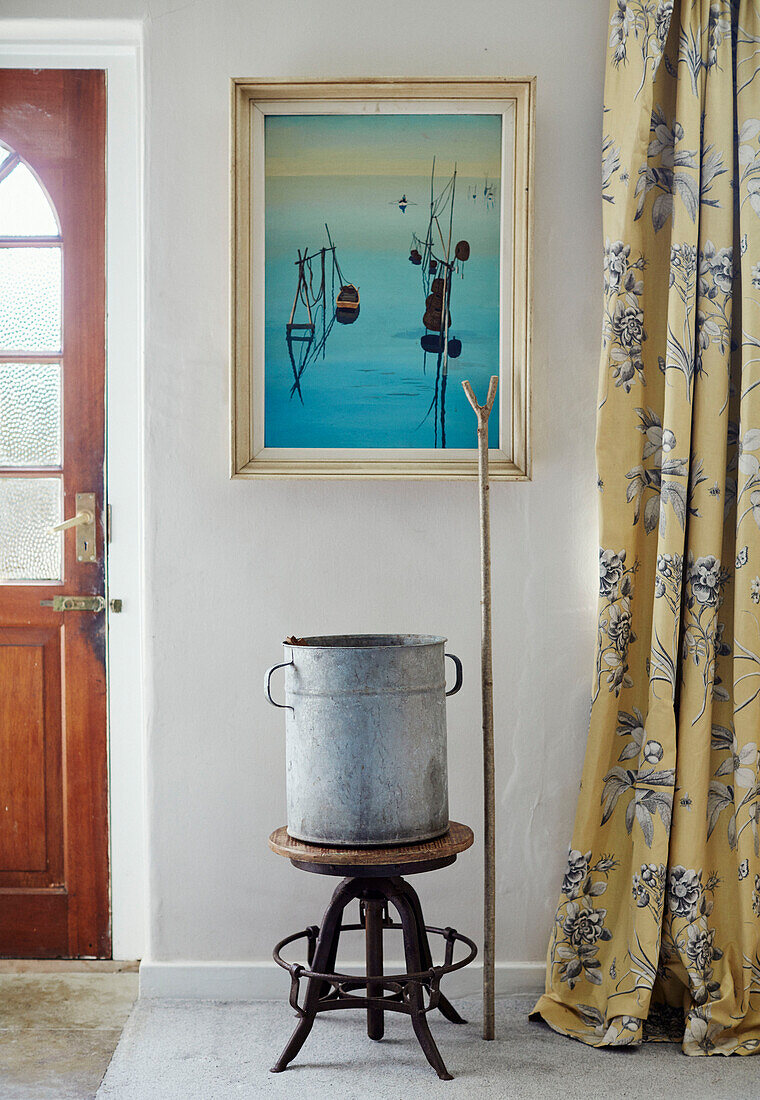 Old metal bucket on antique stool with yellow curtains at entrance to North Yorkshire farmhouse, UK