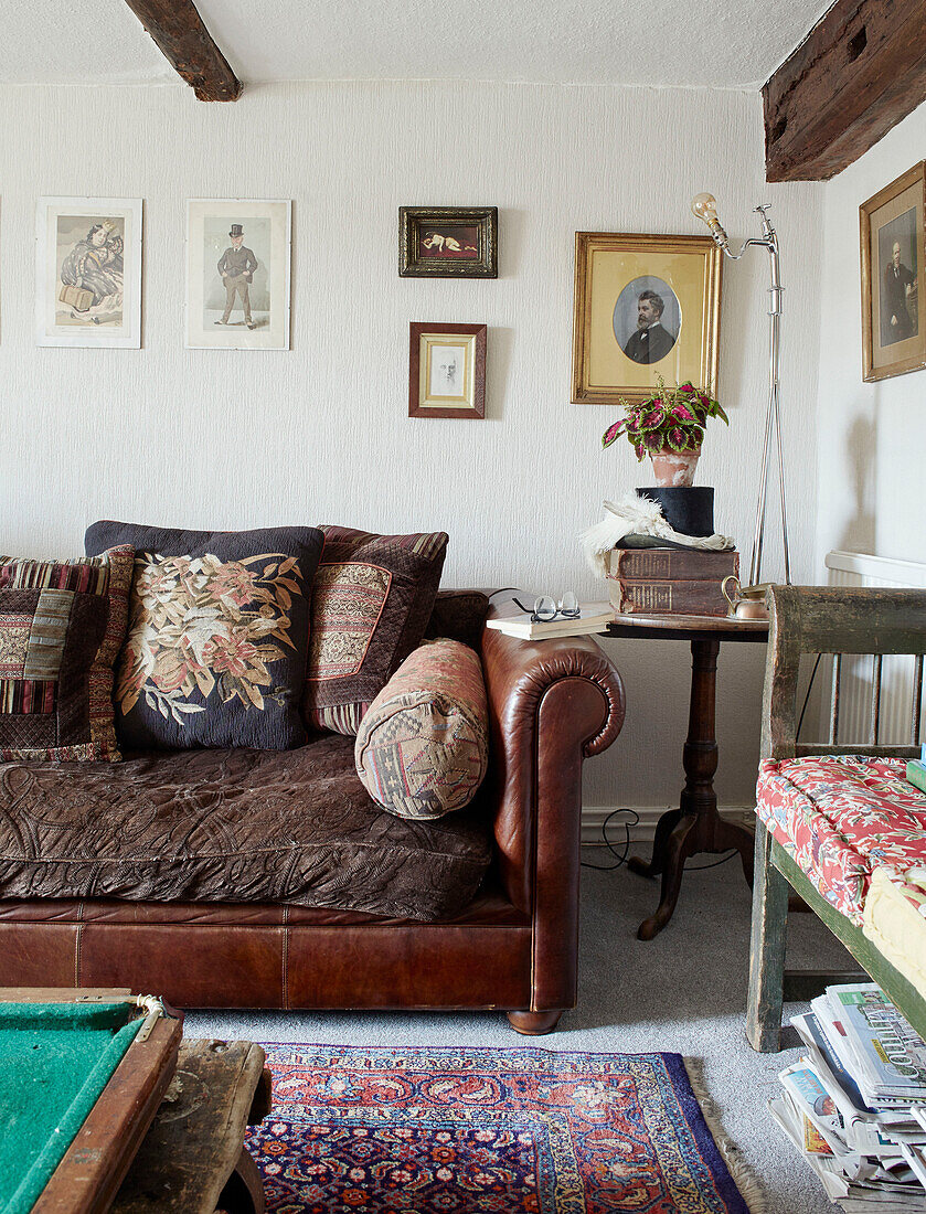Brown leather sofa with embroidered cushions in North Yorkshire farmhouse, UK