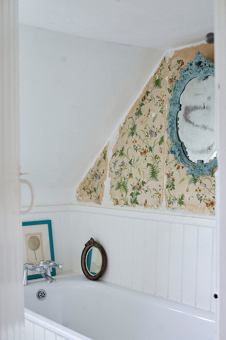 Hellblauer dekorativer Spiegel mit Blumentapete über einer eingelassenen Badewanne in einem Bauernhaus in Oxfordshire, UK