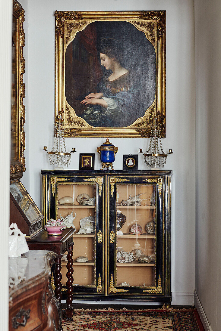 Vergoldetes gerahmtes Kunstwerk über einer Vitrine mit Muscheln in einem Stadthaus in Foix, Ariege, Frankreich