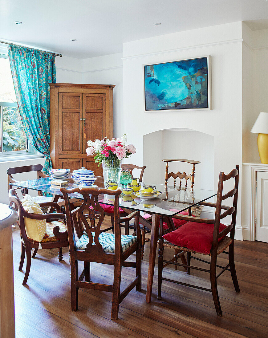 Glass dining table with mismatched vintage chairs in Northern home, UK