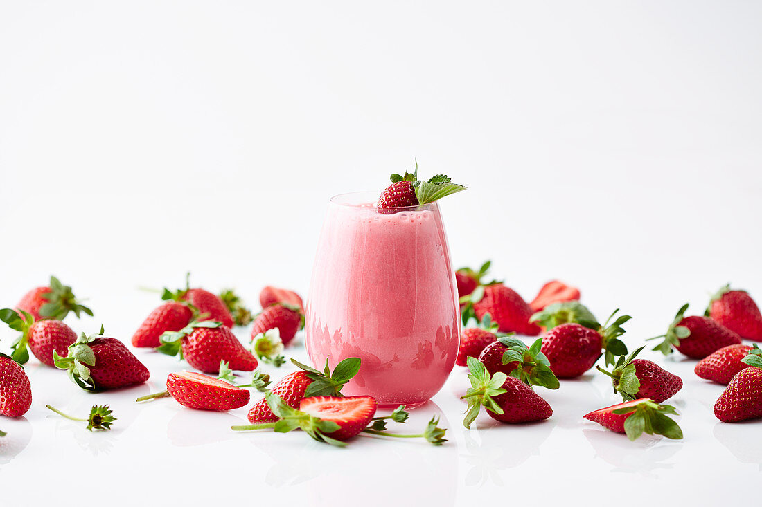 Ein Erdbeersmoothie umgeben von Erdbeeren