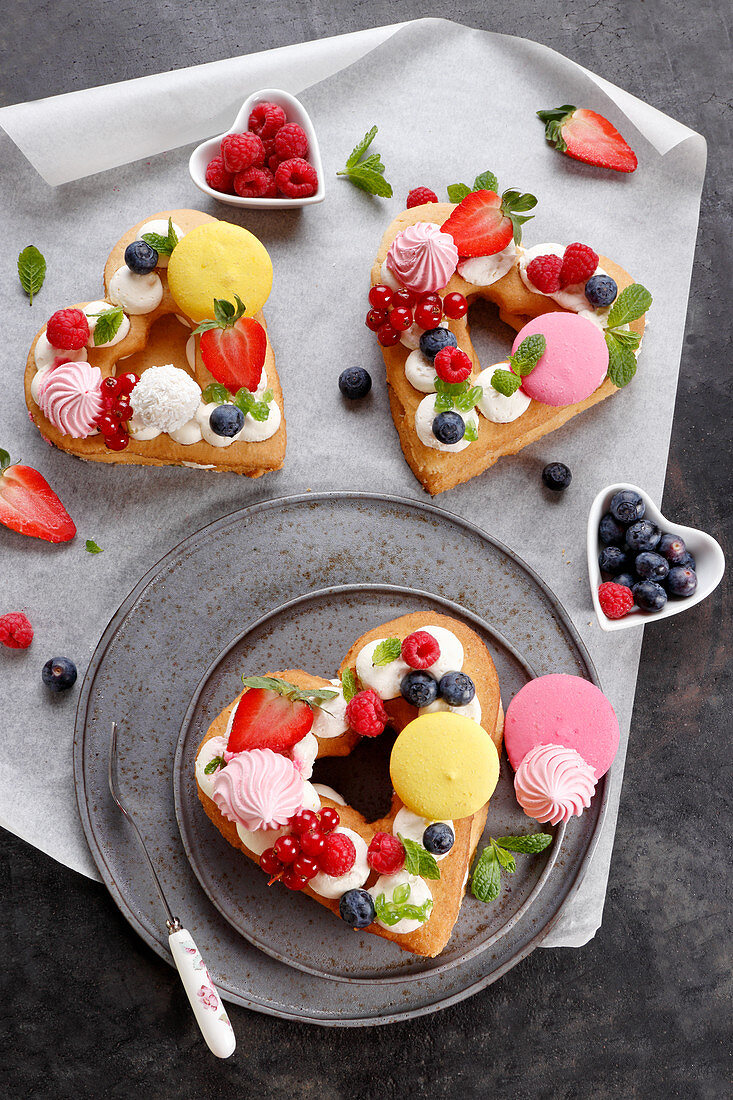 Herzförmige Kuchen mit Baiser, Obst und Macarons