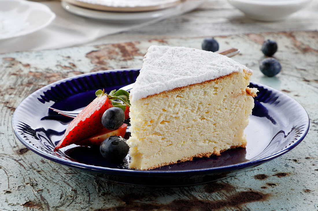 Ein Stück Zitronen-Käsekuchen mit Puderzucker und Beeren