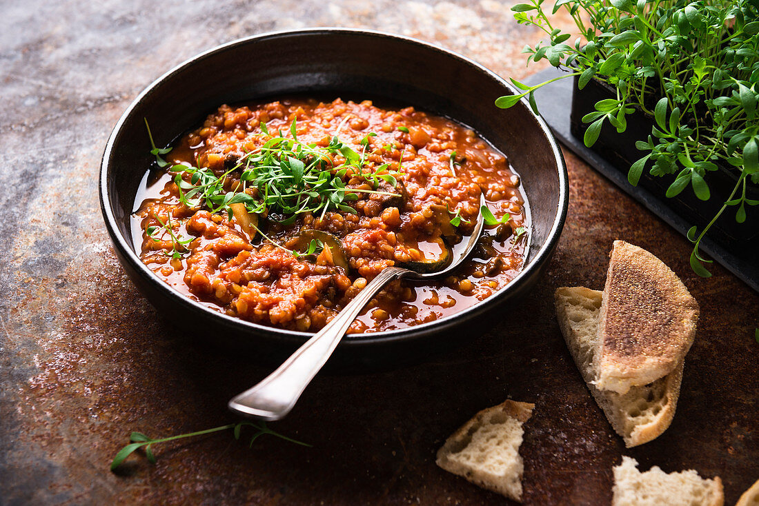 Vegan lentil and tomato soup with courgette and cress