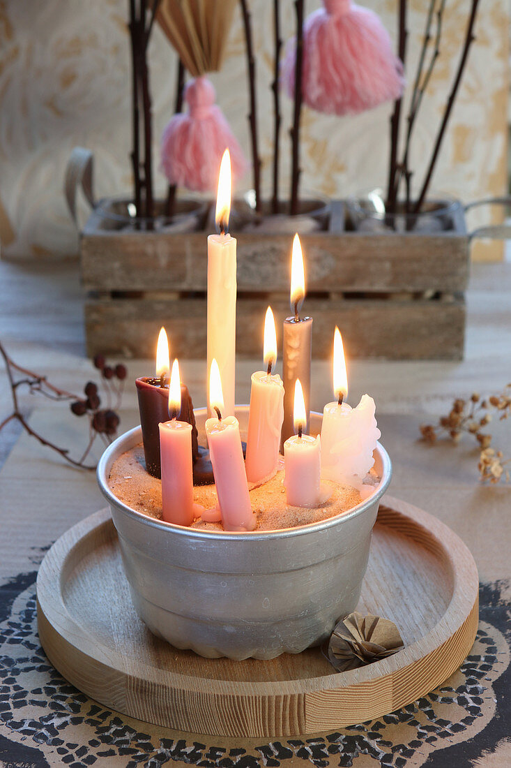 Viele brennende Kerzen in Napfkuchenform mit Sand