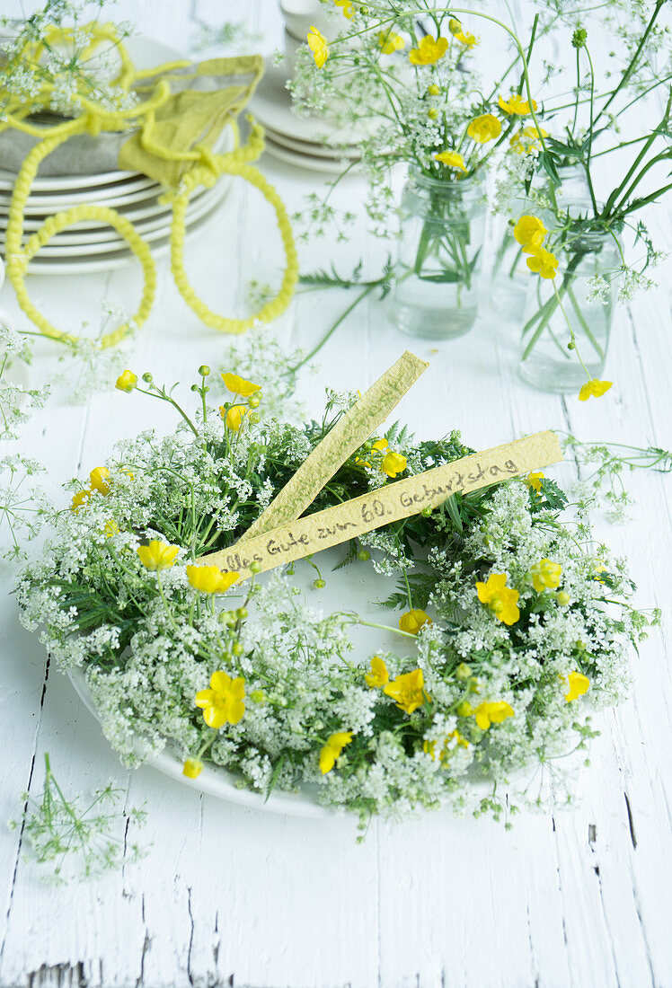 Wreath of cow parsley and buttercups on plate as table decoration for 60th birthday