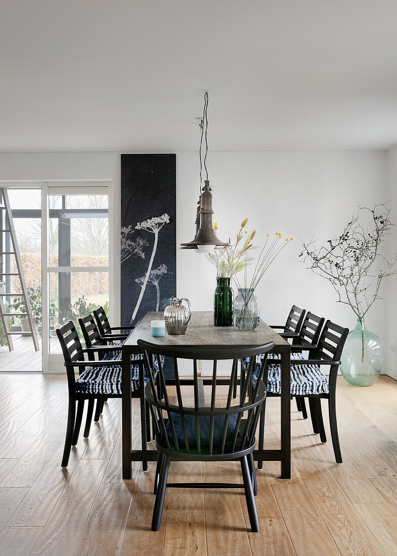 Black chairs around table in dining room with botanical decorations