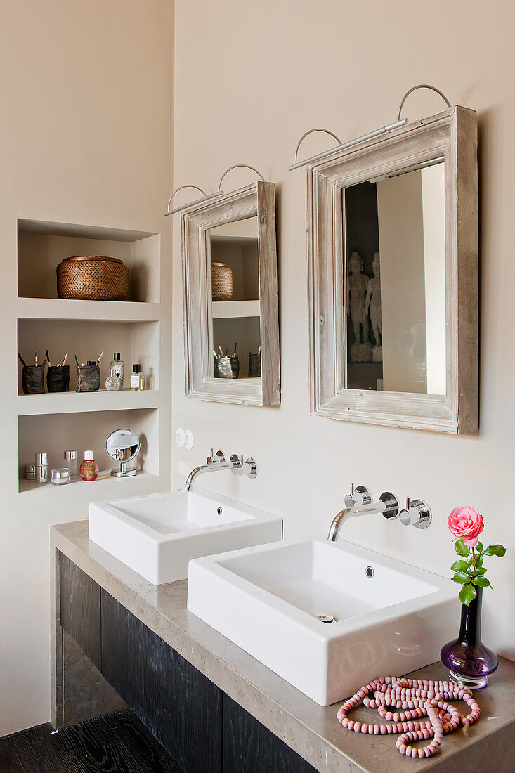 Two mirrors above square twin sinks in beige bathroom