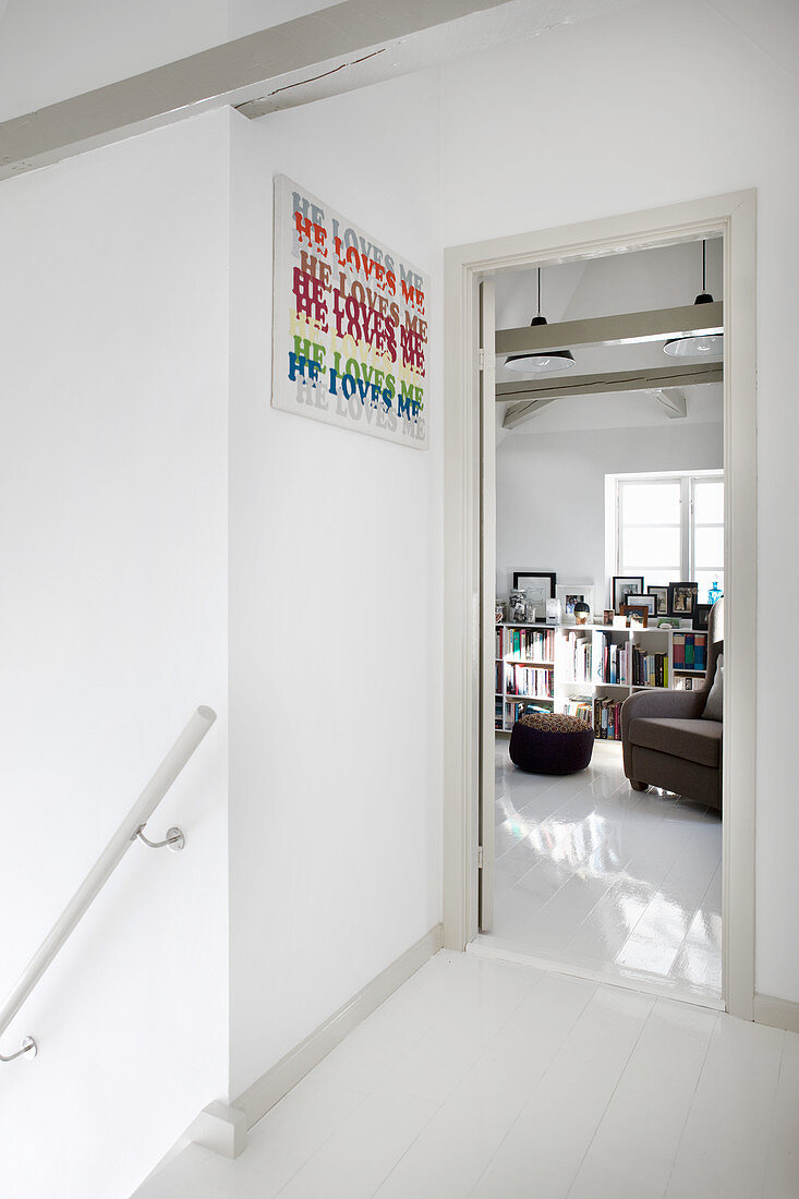 Treppenabsatz im Weiß, Blick ins Arbeitszimmer mit Bücherregal und Sessel