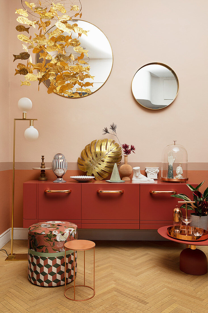 Ornaments on Marsala-red sideboard, gilt leaf, standard lamp and side tables