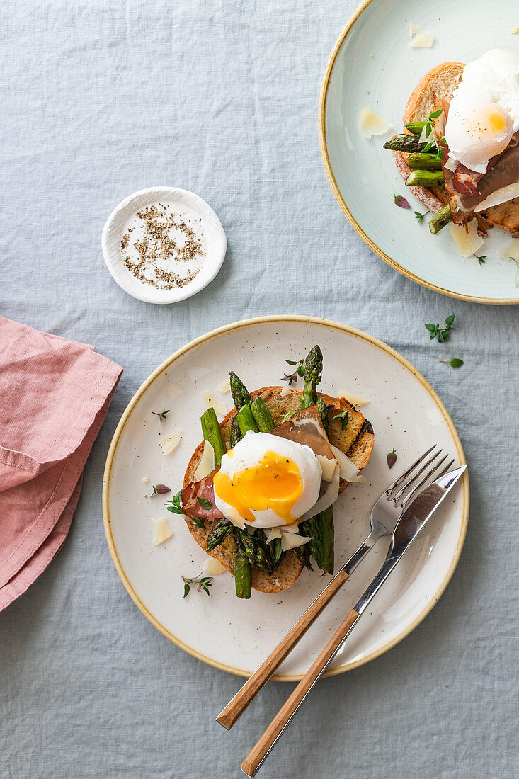 Poached egg on toast with asparagus, ham, parmesan cheese and thyme