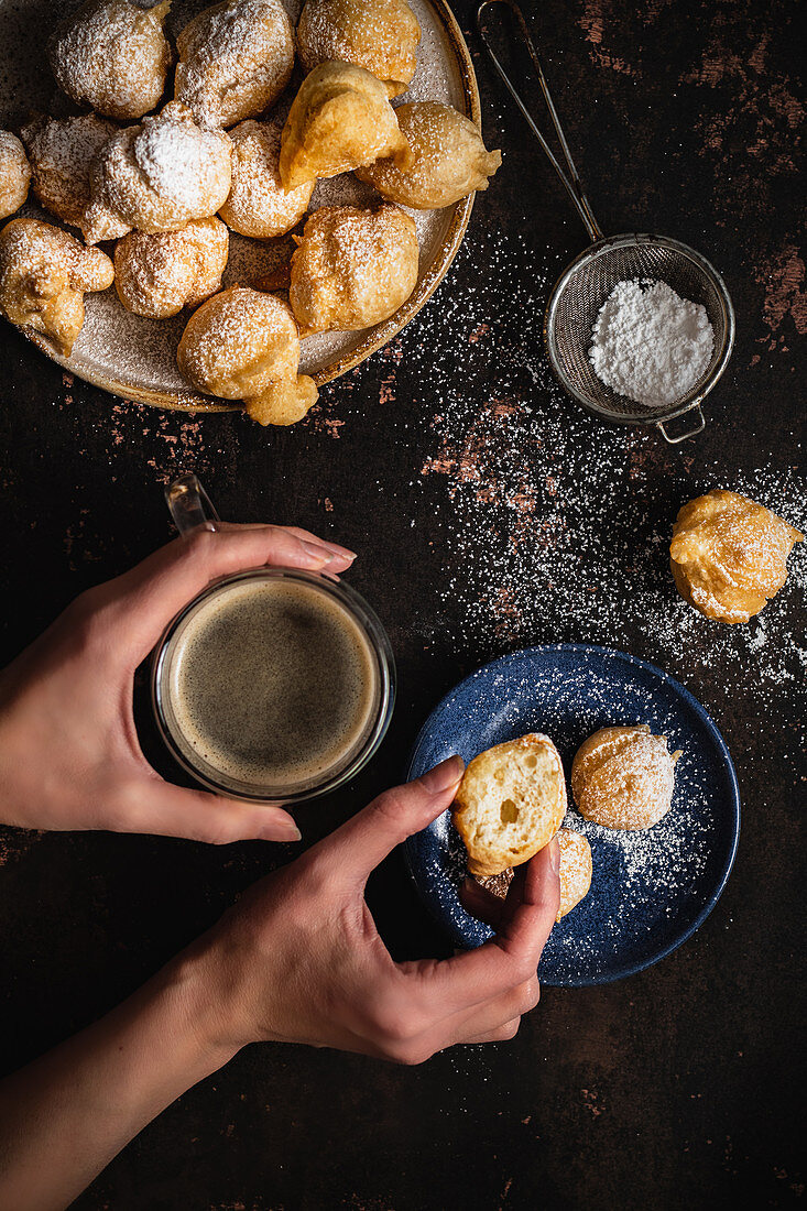 Mini-Donuts mit Puderzucker und Tasse Kaffee