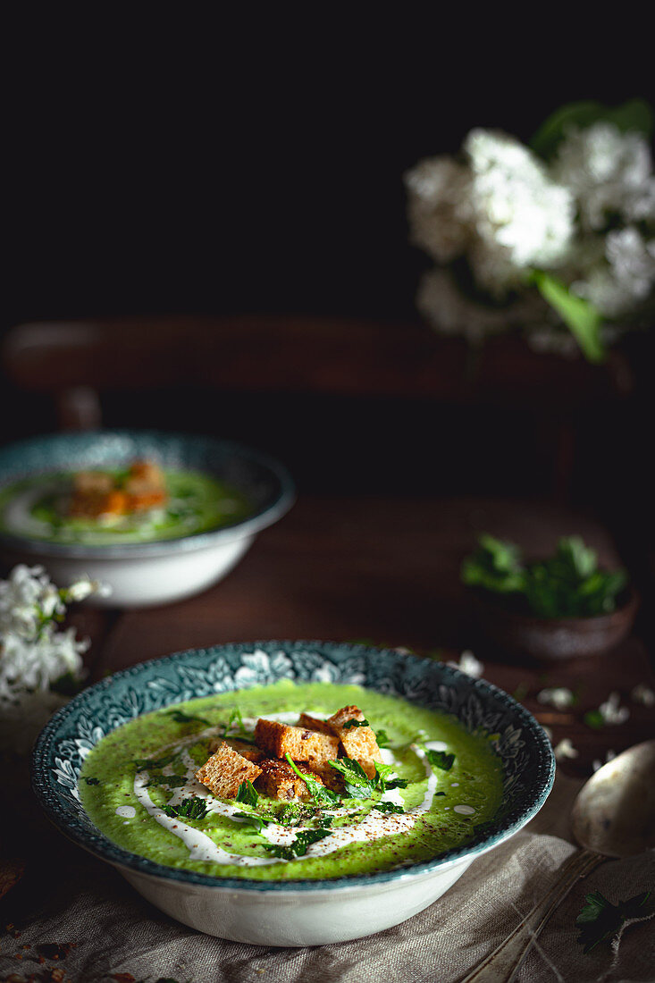 Green pea soup with parsley, cream and croutons
