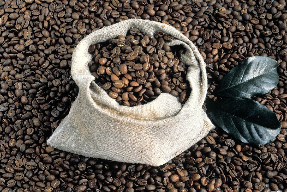 Ein Säckchen mit Kaffeebohnen auf losen Kaffeebohnen