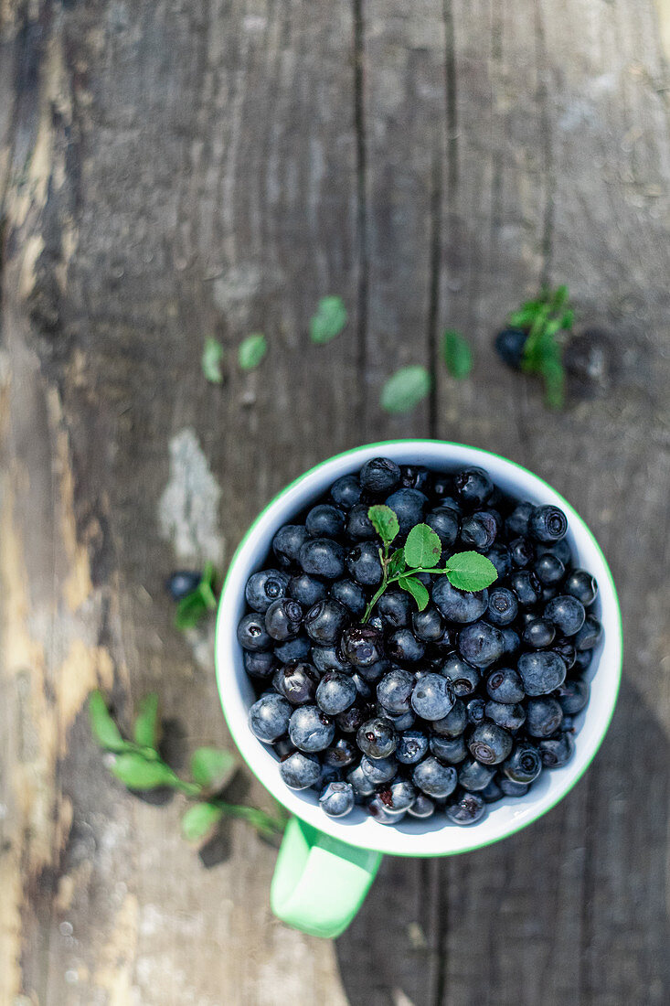 Bilberry in the cup on a wooden background