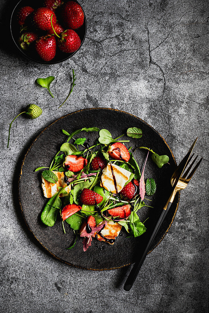 Salad with halloumi strawberries arugula radish leaves and balsamic sauce