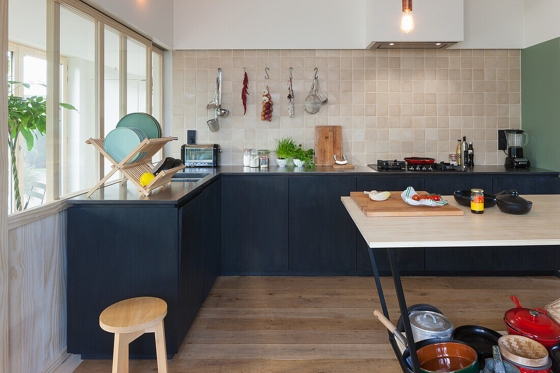 Küche mit hellen Wandfliesen, dunklen Unterschränken und Holzelementen
