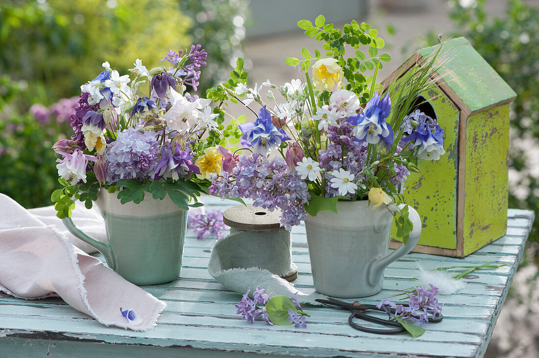 Small bouquets of columbines, lilacs, roses and hornwort in cups