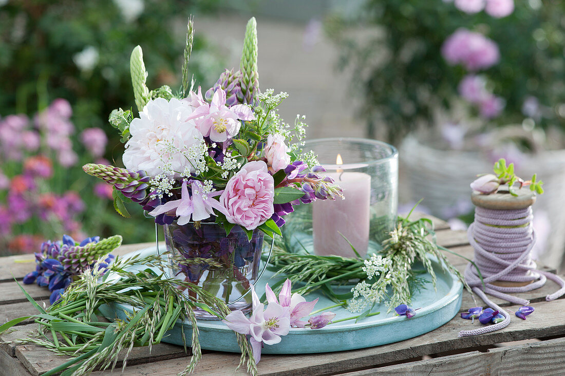 Early summer bouquet with roses, lupins, columbines and cumin, wreaths made of grass and lantern