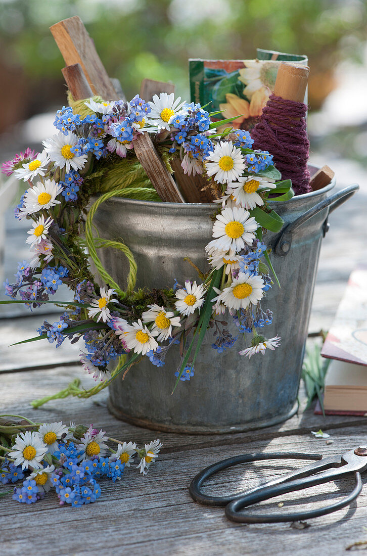 Small wreath of daisies and forget-me-nots on a zinc pot with utensils