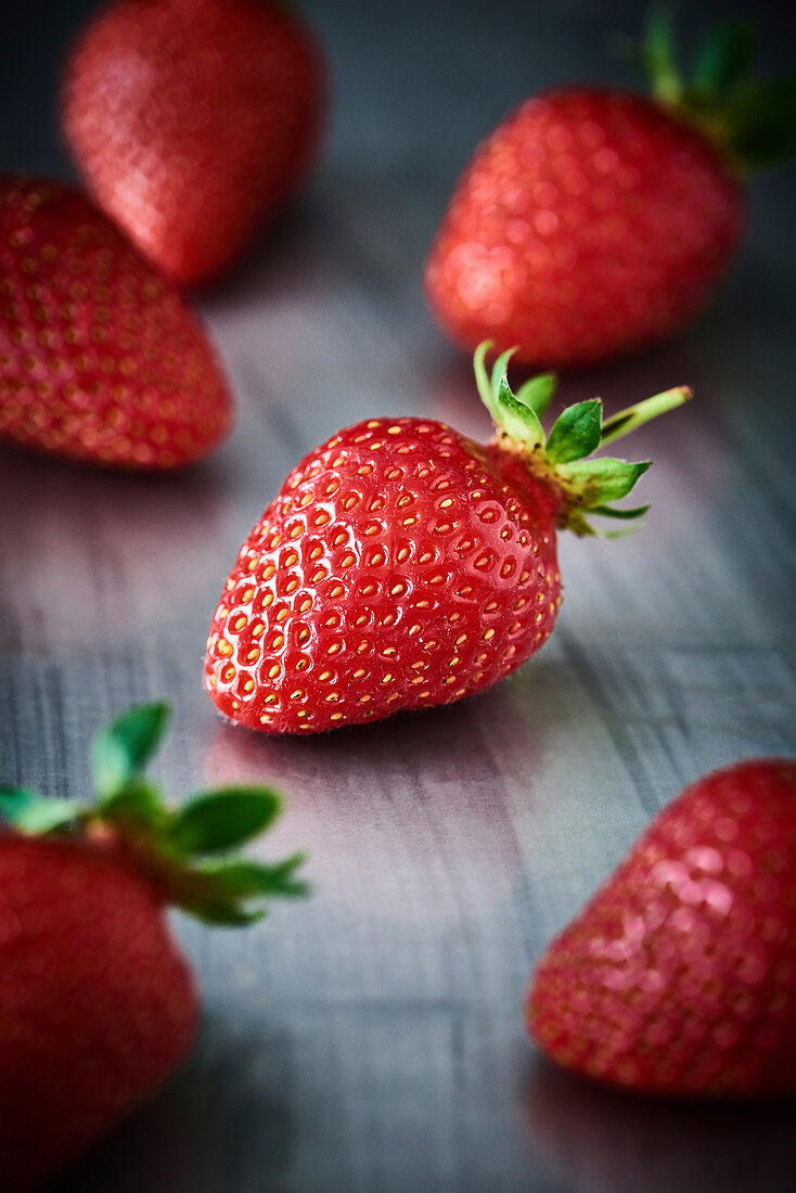 Close Up einer Erdbeere auf einer Metallplatte. Um diese Erdbeere liegen noch 5 andere Erdbeeren