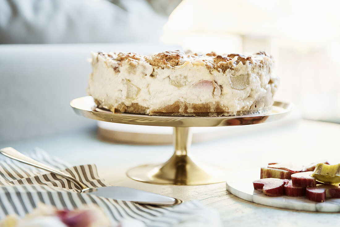 Rhubarb crumble cake with vanilla cream on a golden cake stand